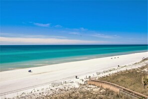 Une plage avec une promenade en bois, une eau turquoise cristalline et un rivage sablonneux.