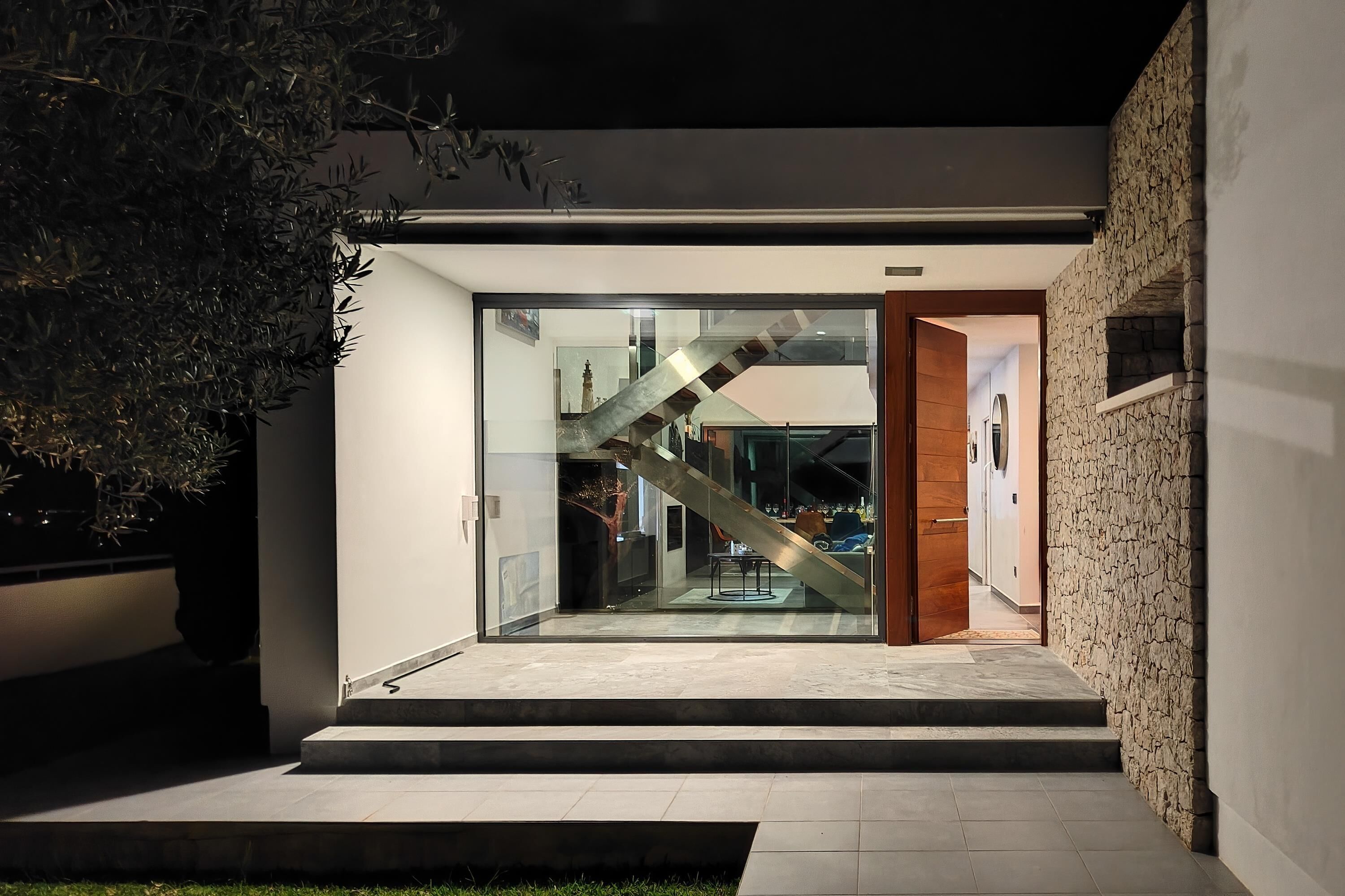 A modern house with a glass door leading to a staircase.