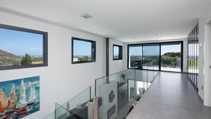 En modern inredning med stora fönster, ett glasräcke och utsikt över havet.
