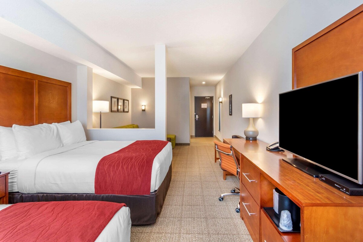 A hotel room with a large bed, a TV, a desk, and a chair.