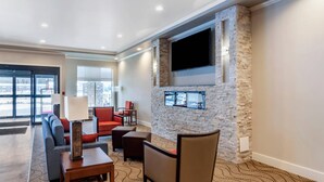 A lobby with a stone fireplace, seating area, and a large TV mounted on the wall. - Comfort Inn & Suites (Valemount)