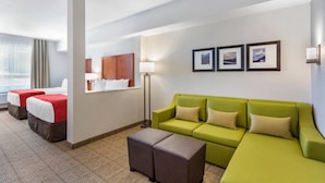 A hotel room with two beds, a green sofa, a floor lamp, and framed pictures on the wall. - Comfort Inn & Suites (Valemount)