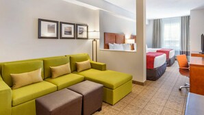 A hotel room with a green sofa, a bed, a desk, and a lamp. - Comfort Inn & Suites (Valemount)