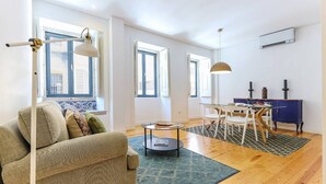 A living room with a sofa, a dining table with chairs, and a blue wall.
