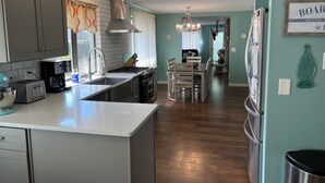 Uma cozinha moderna com uma ilha central, eletrodomésticos de aço inoxidável e uma área de jantar com lustre.