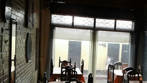 A restaurant with brick walls, large windows, and tables with chairs. - Hotel Capri (Guatemala City)