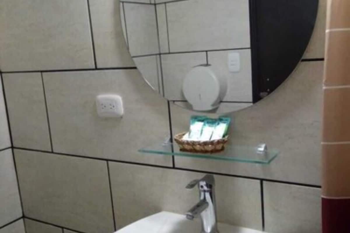 A bathroom with a white sink, a round mirror, and a toilet.