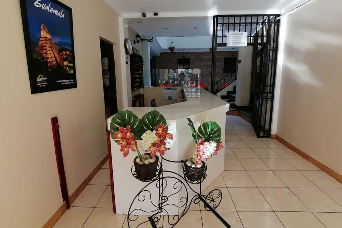 Eine Hotelhalle mit einer Rezeption, einem Poster von Guatemala und einer Treppe zu einer anderen Etage.
