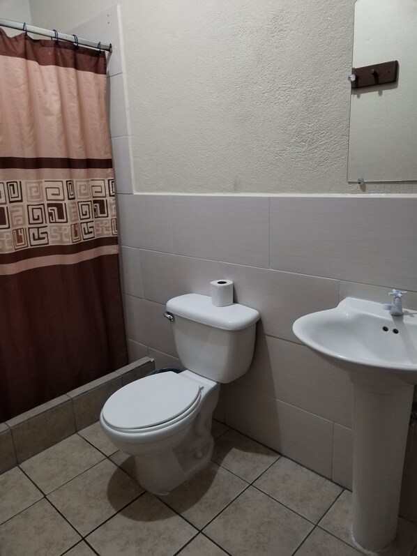 Baño con inodoro, lavamanos y cortina de ducha.