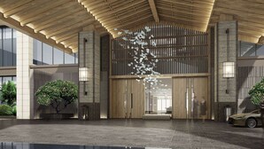 Una entrada de edificio moderna con techo de madera, puertas de cristal amplias y un accesorio de iluminación decorativo.