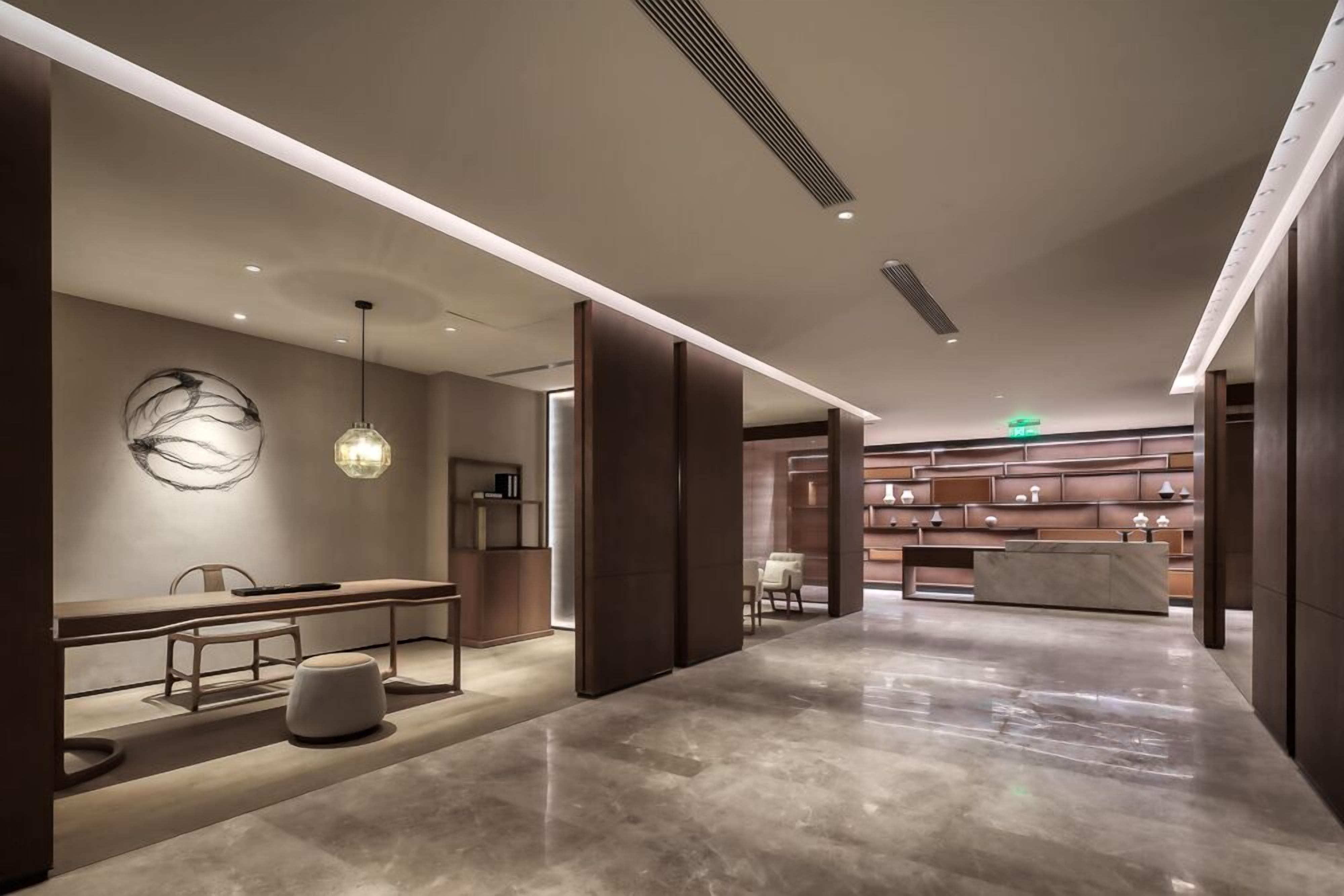 Un hall d’hôtel moderne avec un long comptoir d’accueil, un espace salon et un élément décoratif mural.