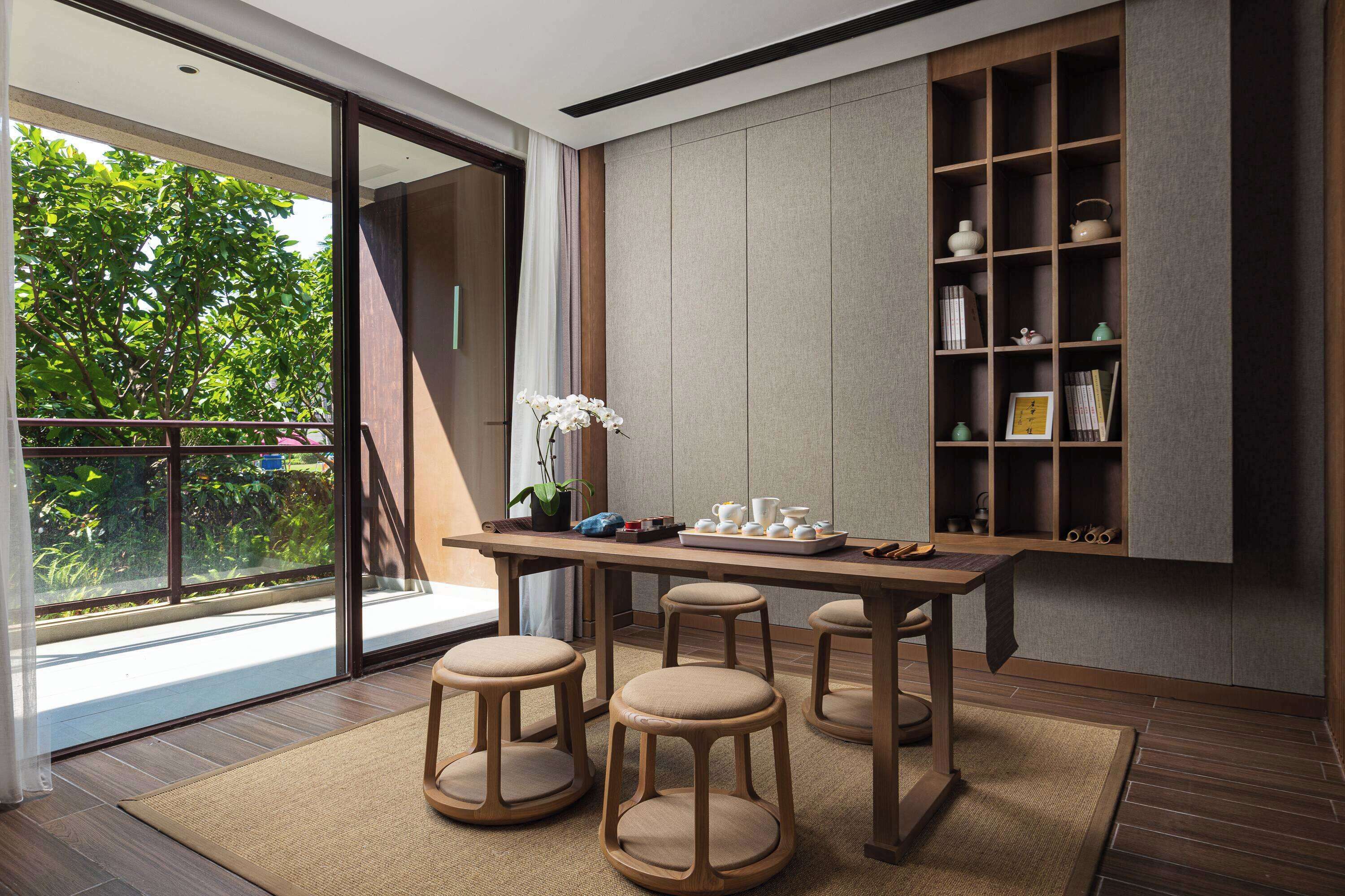 A modern kitchen with a wooden table, stools, and a built-in shelf with kitchenware.