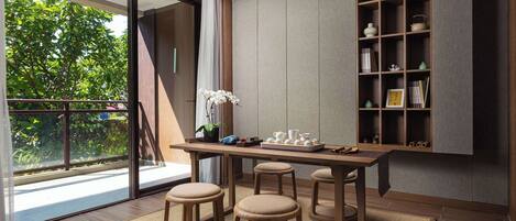 A modern kitchen with a wooden table, stools, and a built-in shelf with kitchenware.