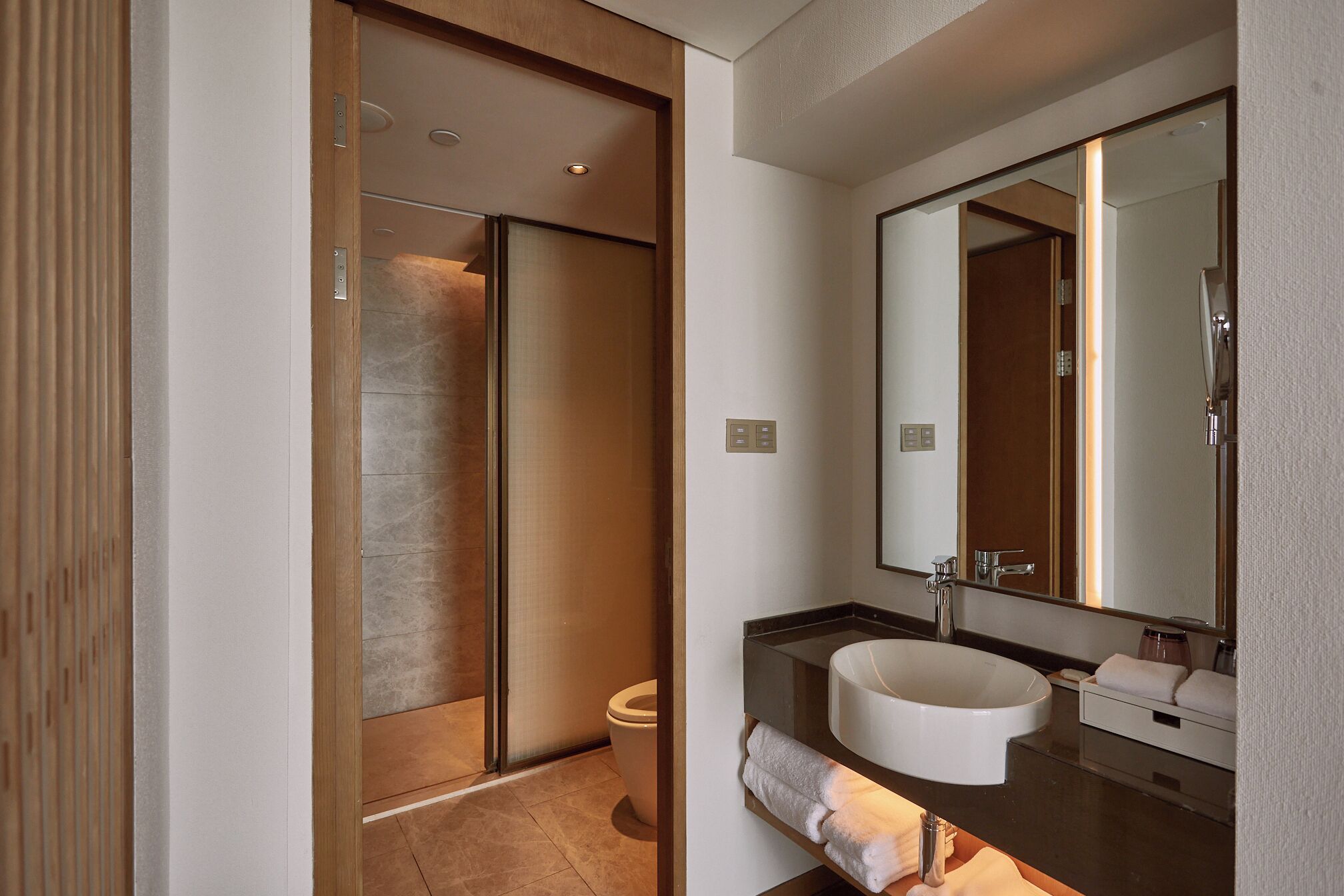 Un baño moderno con cabina de ducha, un lavabo con espejo y un perchero para toallas.