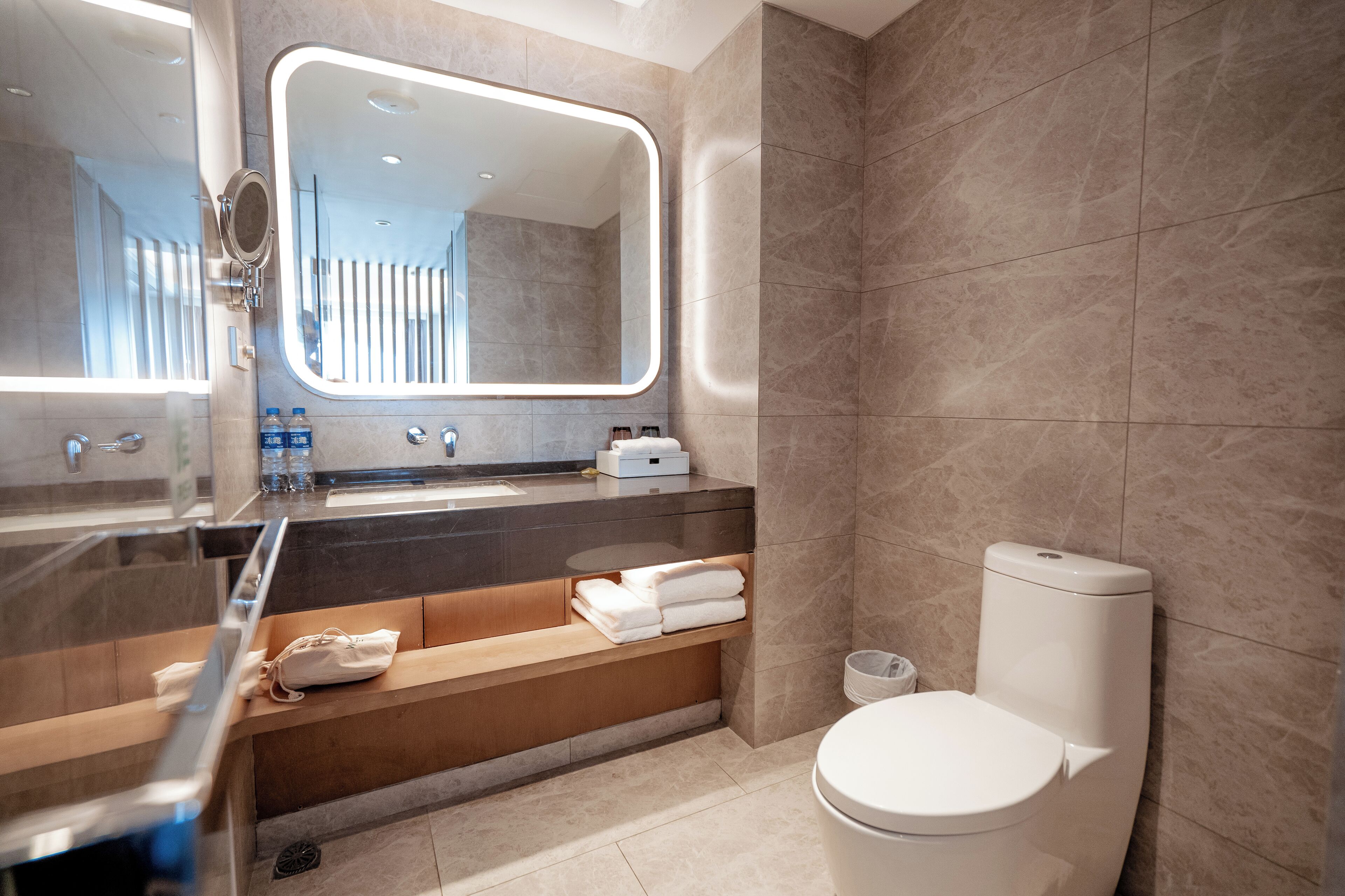 Un baño moderno con un espejo grande, una bañera, un inodoro y un lavabo.