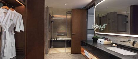 Une salle de bain moderne avec un grand miroir, des meubles en bois foncé et une douche intégrée.
