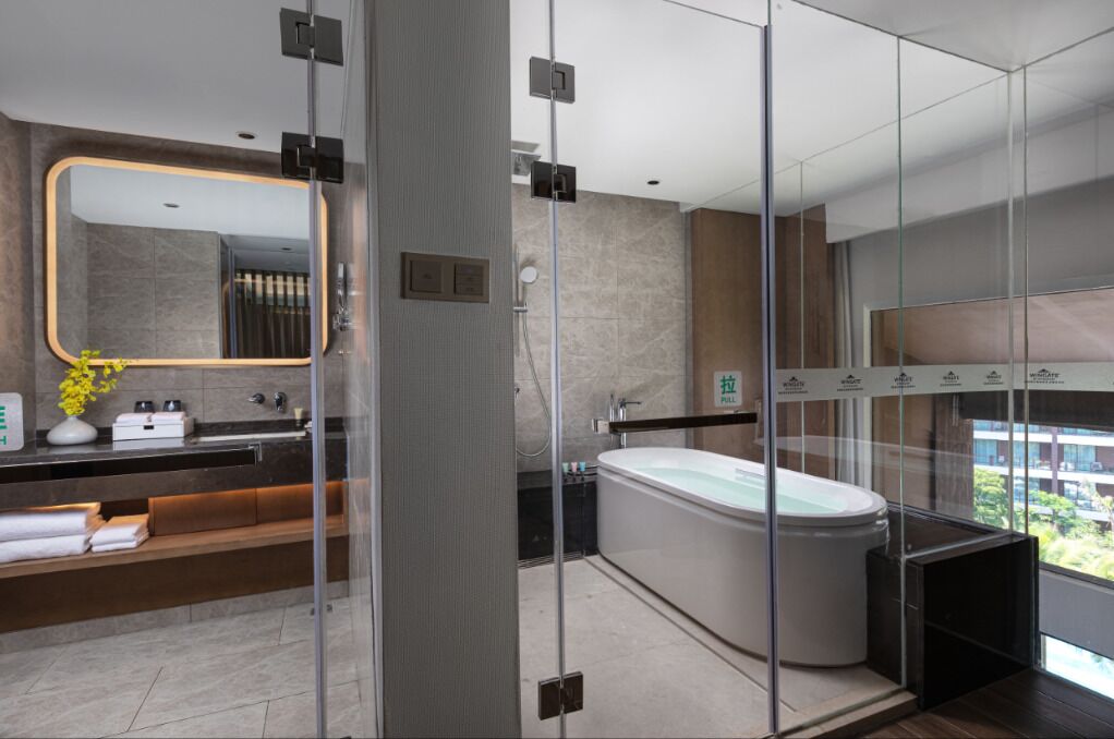 A modern bathroom with a glass-enclosed shower, a large mirror, a bathtub, and a vanity with a built-in sink.
