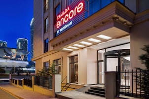 Entrada de un hotel con un letrero destacado que dice "RAMADA encore by WYNDHAM".
