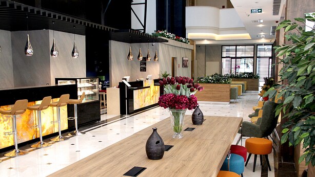 A modern hotel lobby with a reception desk, bar area, and seating. - Ramada Encore By Wyndham Istanbul Basin Express (Istanbul)