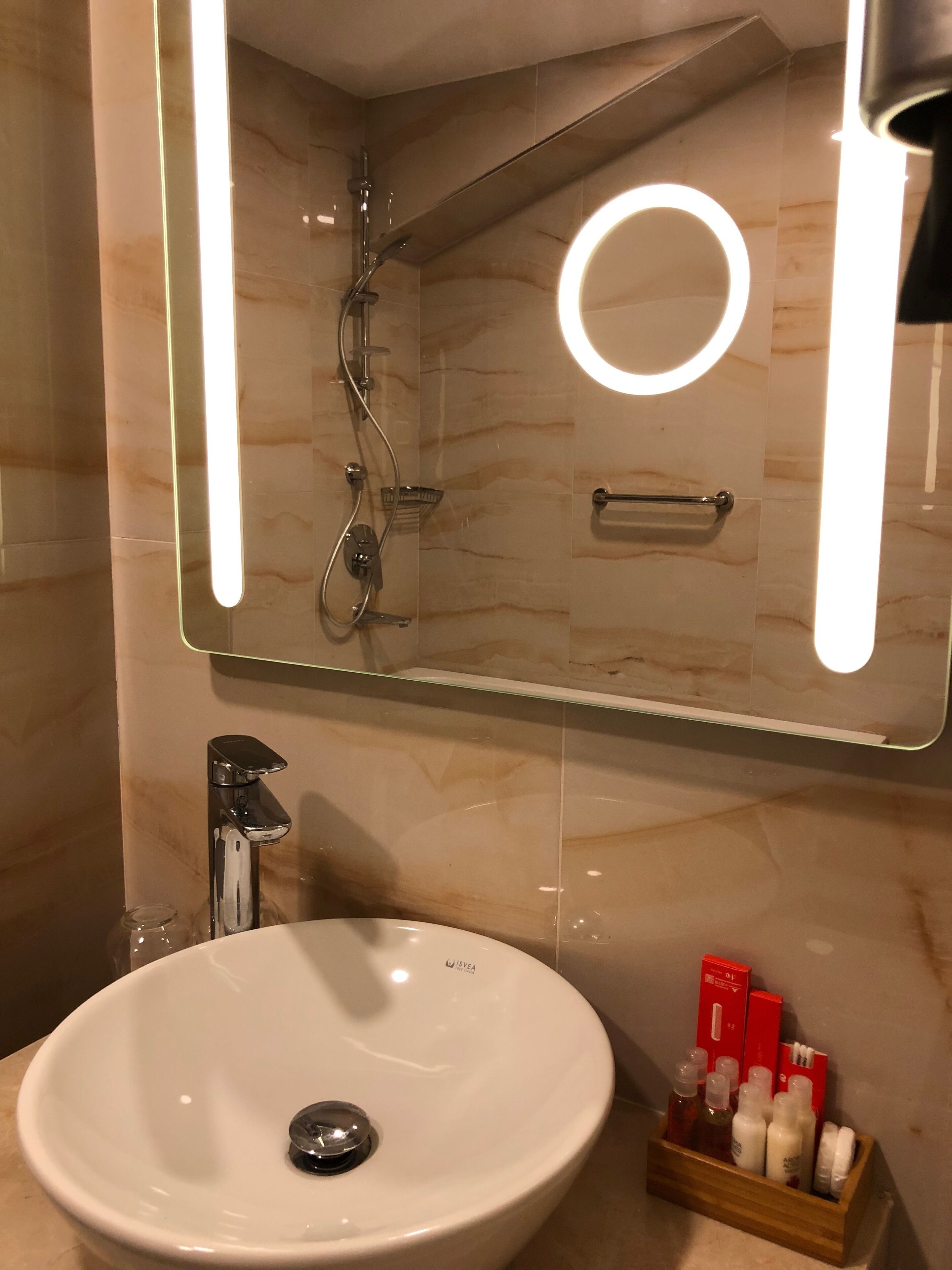 A bathroom with a white sink, a mirror with a light, and a shower.