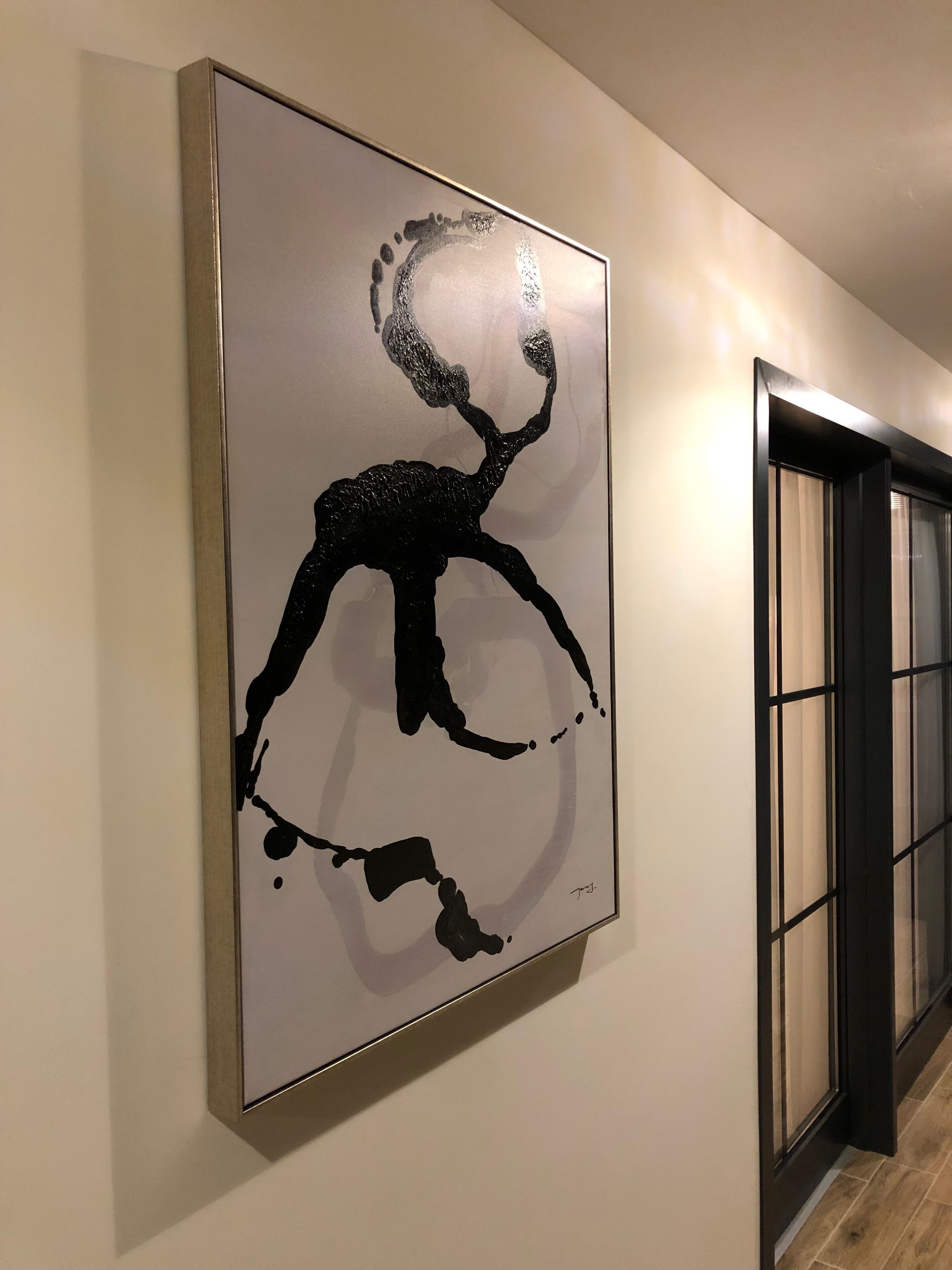 A hallway with a framed abstract artwork on the wall.