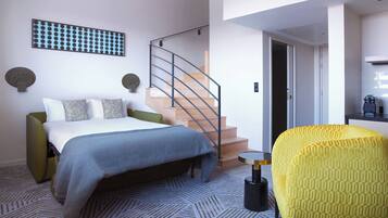 A modern bedroom with a bed, a staircase, and a yellow armchair.