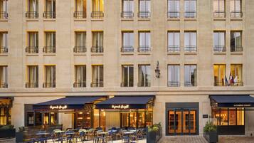 Experience the hotel's elegant entrance, featuring a beautifully designed facade with evenly spaced windows and balconies, and an inviting outdoor seating area.