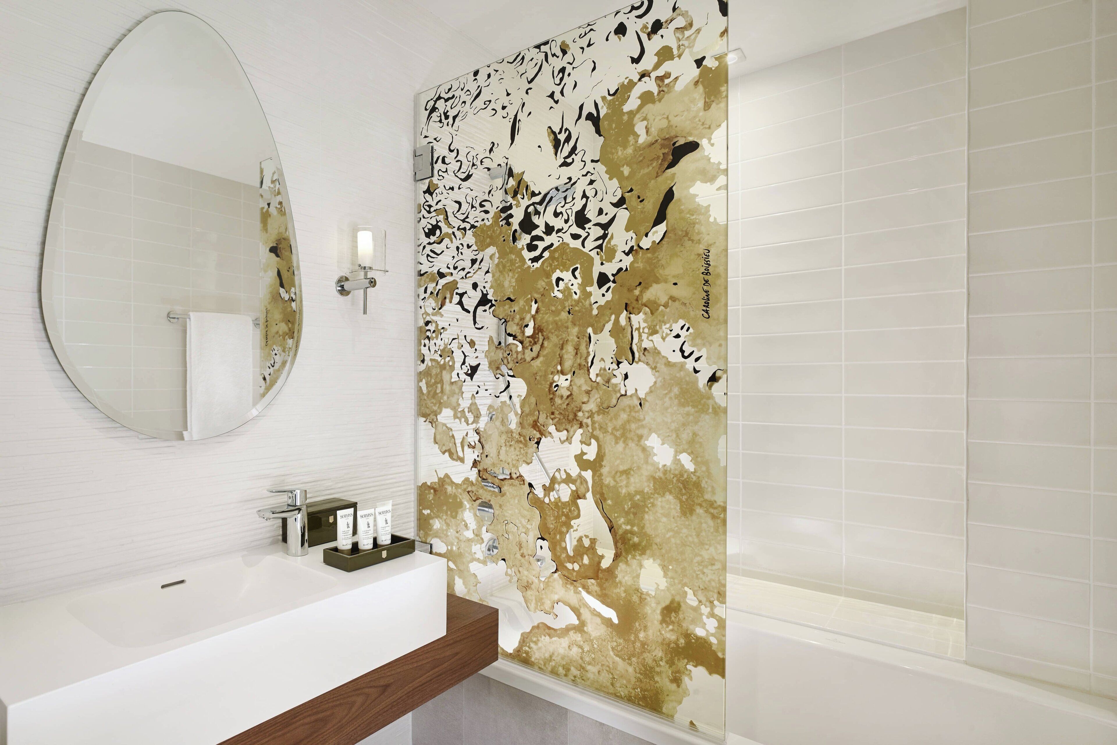 Une salle de bain avec un lavabo blanc, un miroir et un espace douche.