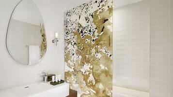 Une salle de bain avec un lavabo blanc, un miroir et un espace douche.