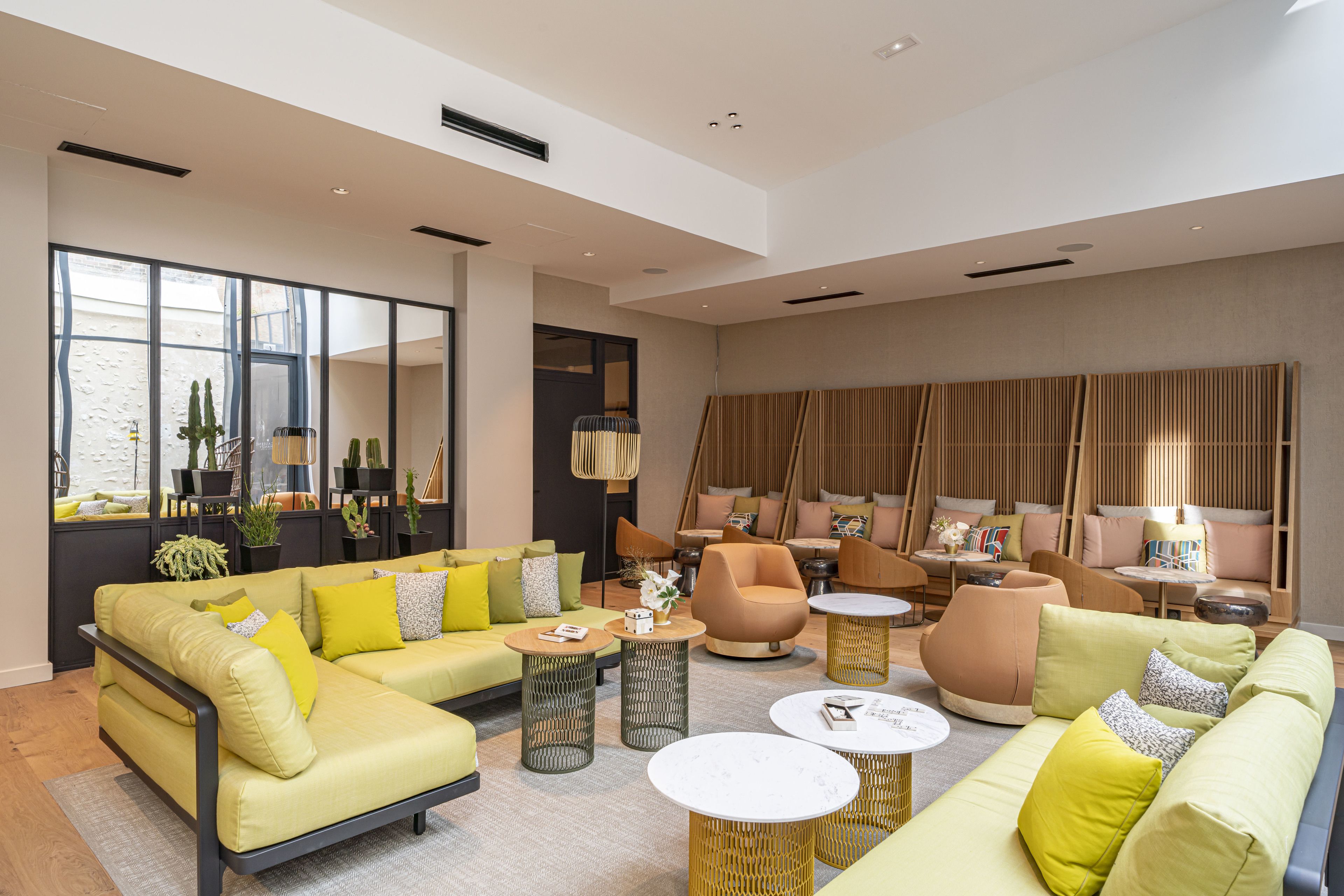 A spacious living room with a yellow sofa set, multiple seating options, and a large window providing natural light.