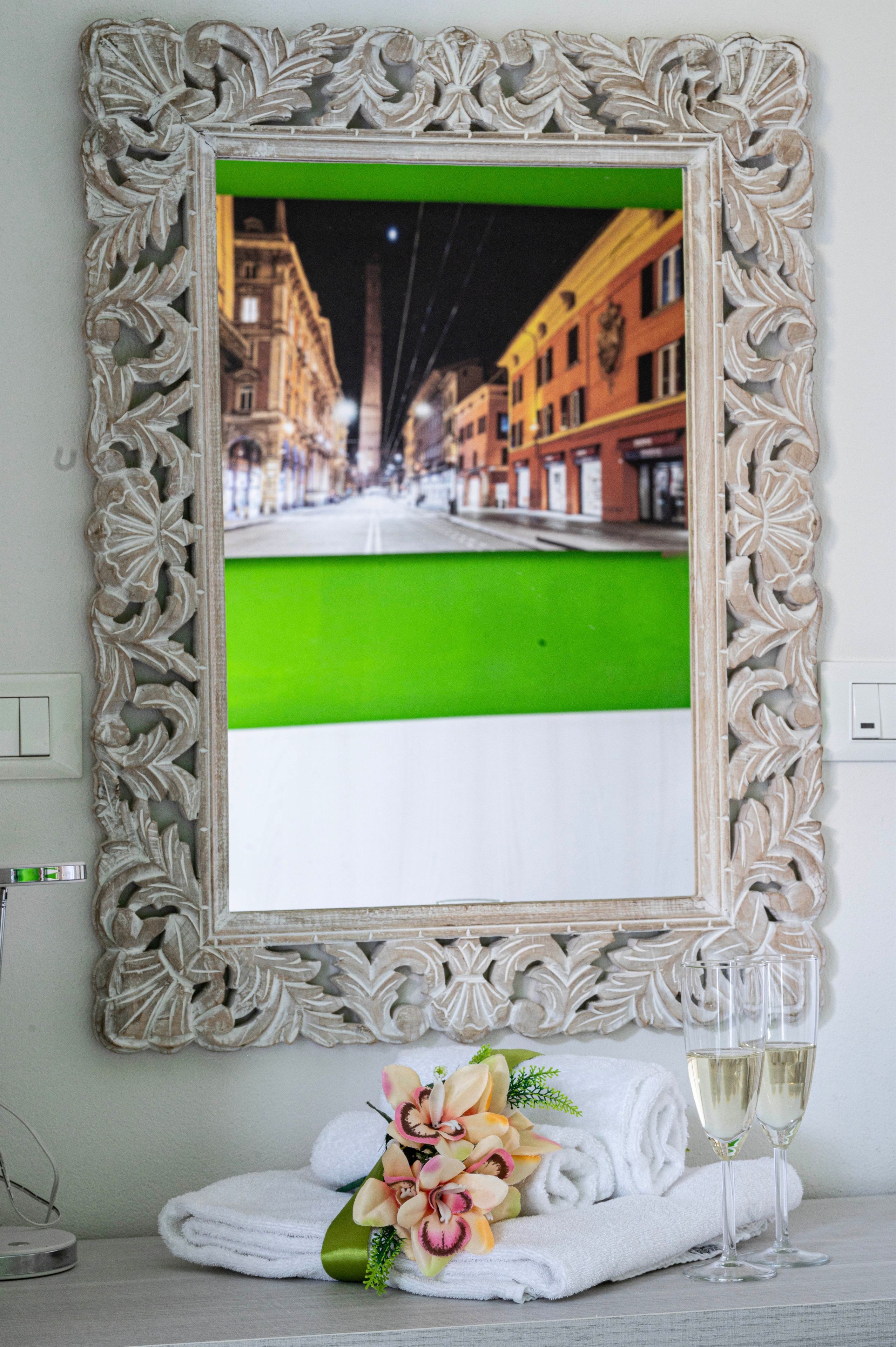 A framed picture with a green and white color split, a bouquet of flowers, and two glasses of white wine on a table.
