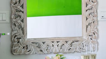 A framed picture with a green and white color split, a bouquet of flowers, and two glasses of white wine on a table.
