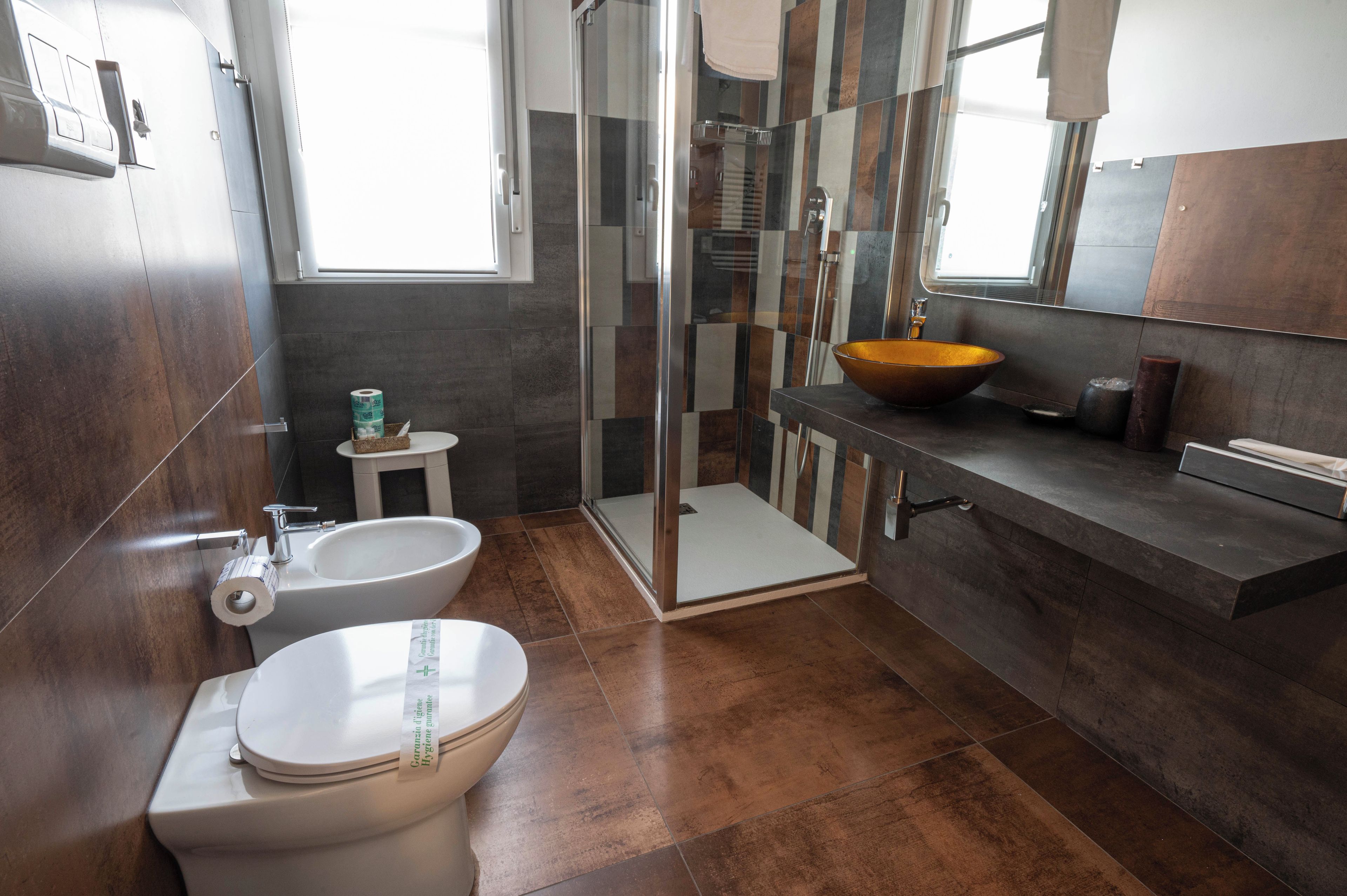 A modern bathroom with a toilet, bidet, and a large sink with a bowl.