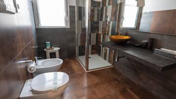 A modern bathroom with a toilet, bidet, and a large sink with a bowl.