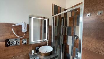 Un baño de diseño moderno, con un espejo grande, un lavabo con un recipiente redondo y una ducha con cerramiento de vidrio.