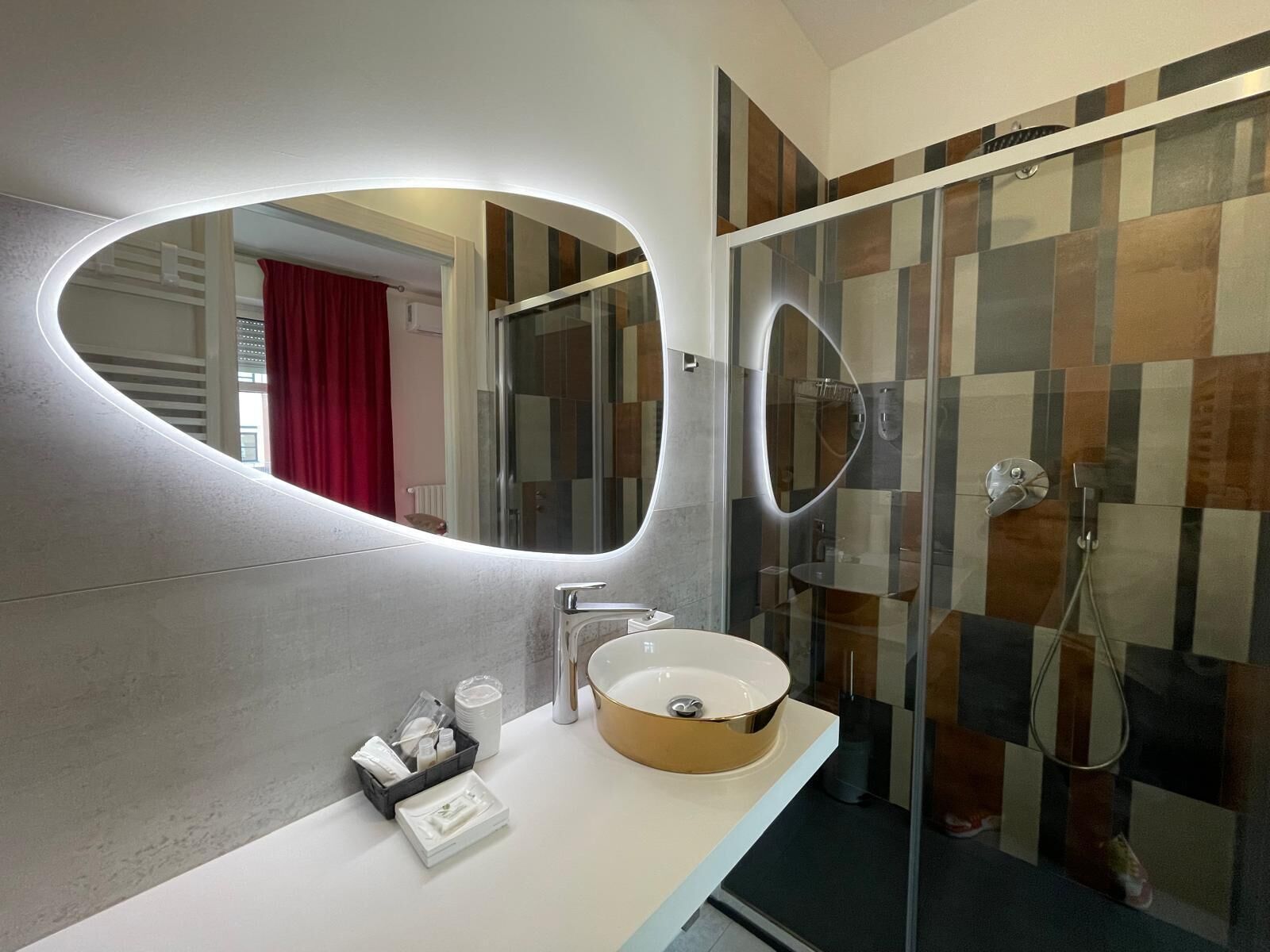 Ein modernes Badezimmer mit einem runden Waschbecken, einem großen Spiegel und einer Duschkabine.