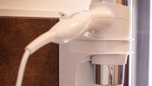 A hair dryer mounted on a wall with a coiled cord. - B&B Bologna Fair Tower (Bologna)