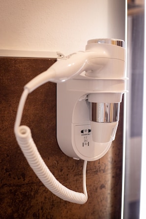 A hair dryer mounted on a wall with a coiled cord. - B&B Bologna Fair Tower (Bologna)