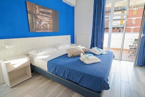 Una habitación de hotel con una cama, una mesita de noche, una ventana con cortinas y vistas a edificios.