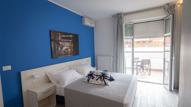 A bedroom with a large bed, a nightstand, a radiator, and a view of the outside balcony. - B&B Bologna Fair Tower (Bologna)