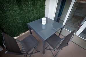 A glass-top table with four metal chairs, a white object on the table, and a green wall. - B&B Bologna Fair Tower (Bologna)