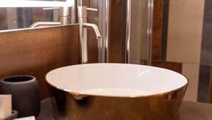 A bathroom with a round, gold-colored sink, a modern faucet, and a large mirror. - B&B Bologna Fair Tower (Bologna)