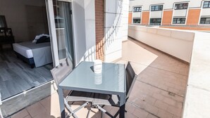 A balcony with a glass table and chairs, a bed, and a brick wall. - B&B Bologna Fair Tower (Bologna)