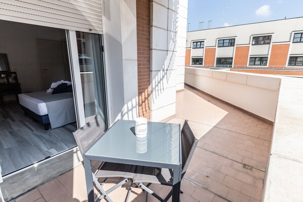 A balcony with a glass table and chairs, a bed, and a brick wall. - B&B Bologna Fair Tower (Bologna)