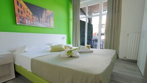 A hotel room with a large bed, a green accent wall, and a painting of a street scene. - B&B Bologna Fair Tower (Bologna)