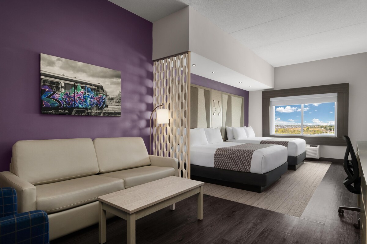 Une chambre d’hôtel avec un lit, un canapé, un bureau et une fenêtre donnant sur un paysage agréable.