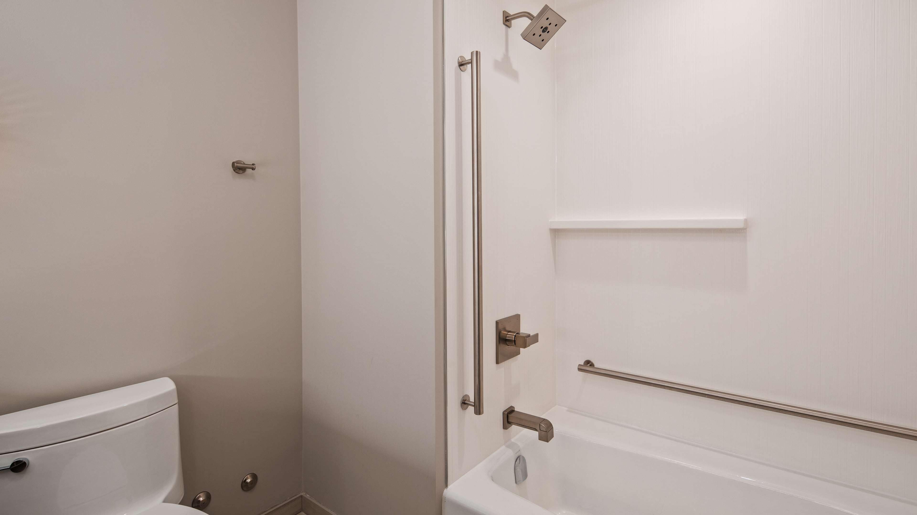 A bathroom with a toilet, a bathtub, and a shower area.