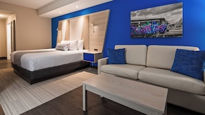 A modern hotel room with a bed, a sofa, a coffee table, and a painting of graffiti on the wall. - Best Western Premier Winnipeg East (Winnipeg)