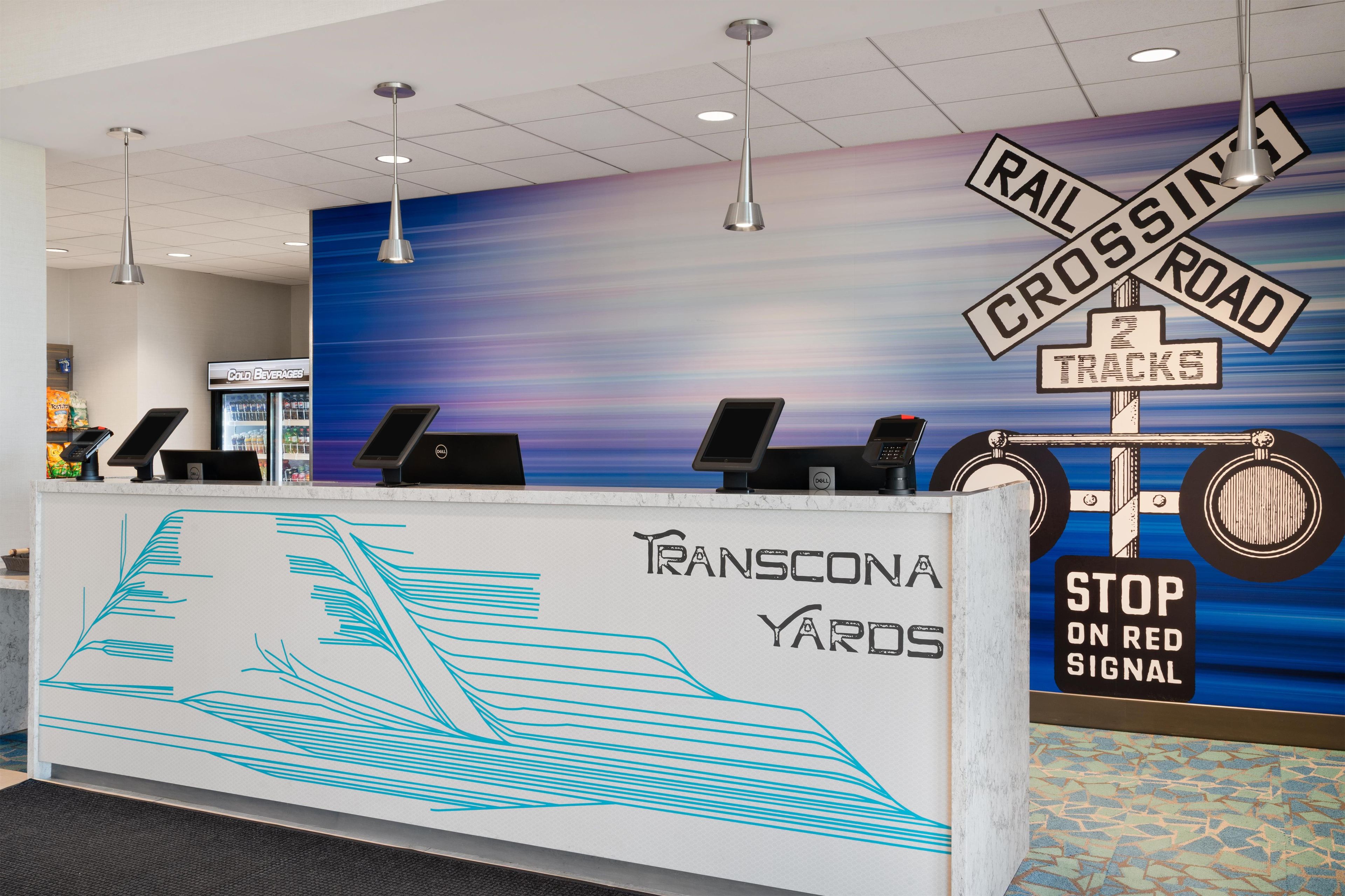 A reception desk with a blue and white design, a 'Railroad Crossing' sign, and a 'Stop on Red Signal' sign.