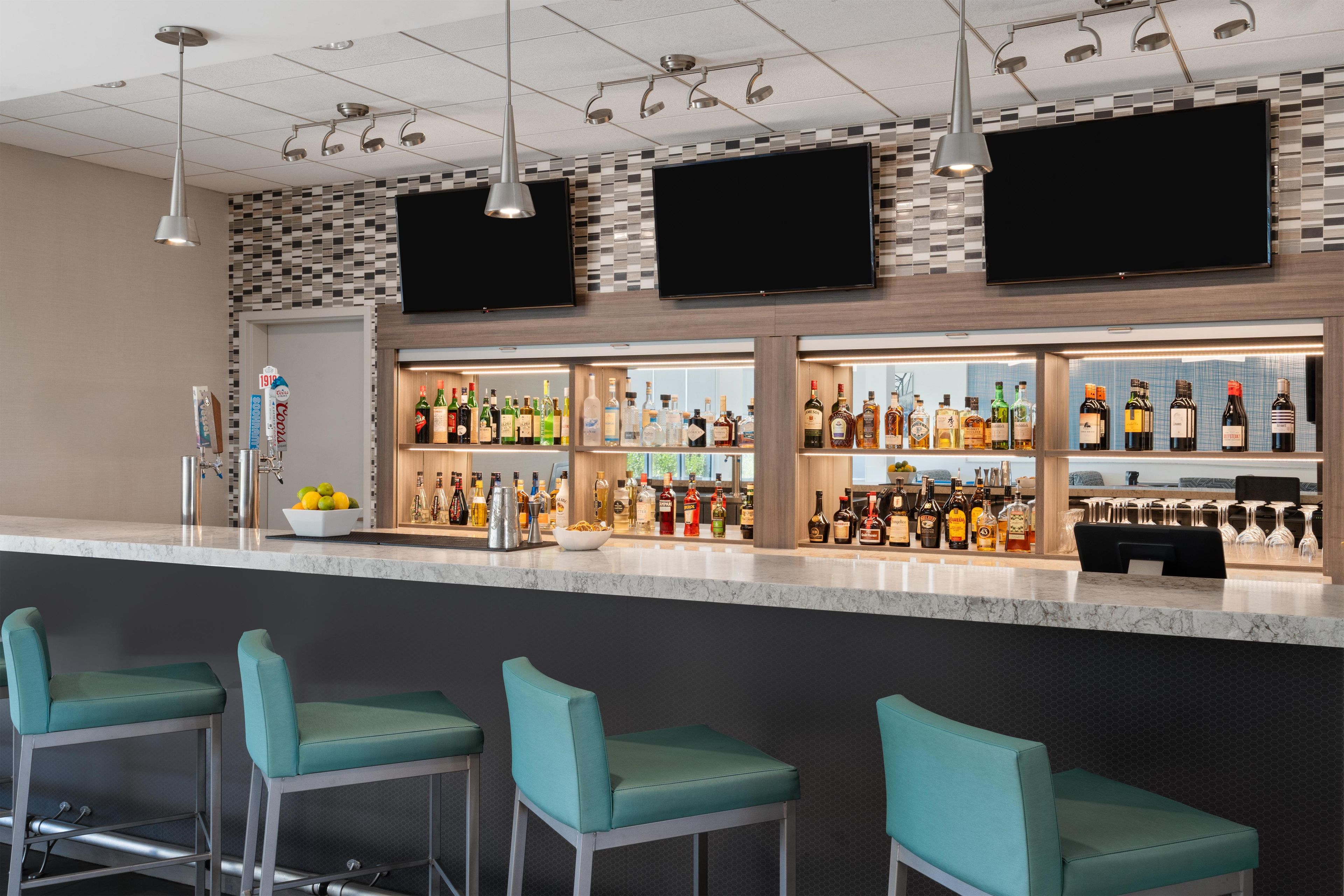 Un espace bar offrant différents types de sièges et une grande variété de bouteilles d’alcool.